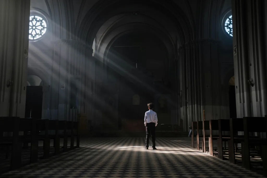 A person standing in a cathedral with light shining in—symbolizing a journey into the Catholic faith