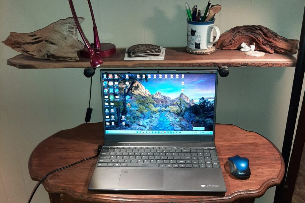 Laptop on rustic wooden desk with books and trinkets – symbolizing storytelling and reflection.