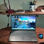 Laptop on rustic wooden desk with books and trinkets – symbolizing storytelling and reflection.